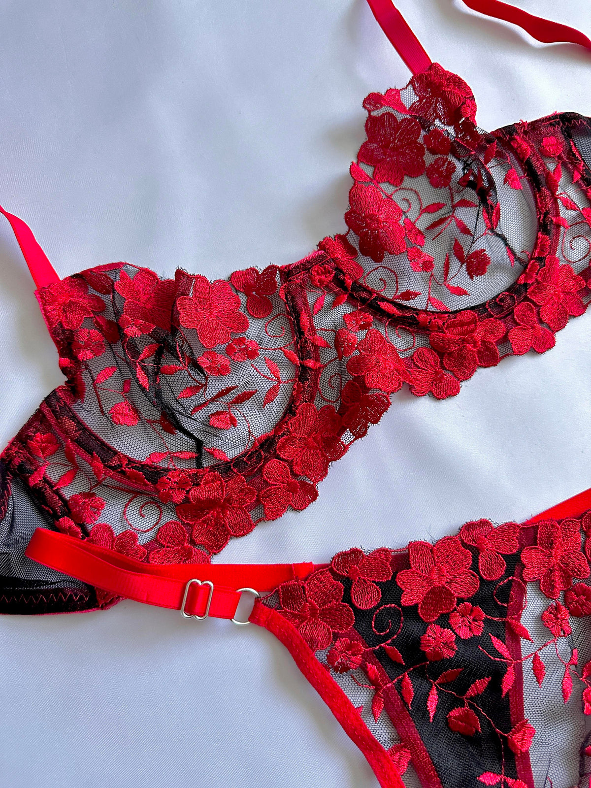 Red embroidered floral pattern on black tulle.